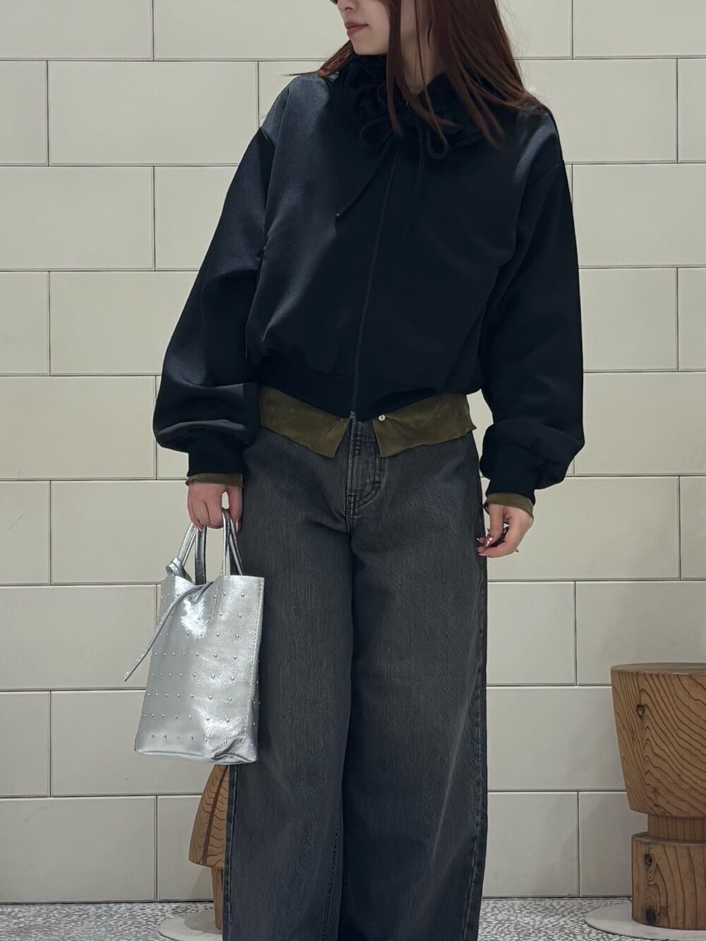 ブラック系のブルゾン、グリーン系のカーディガン/ボレロ、ブラック系のデニムパンツを着用したレディースの冬コーディネートの5枚目の写真