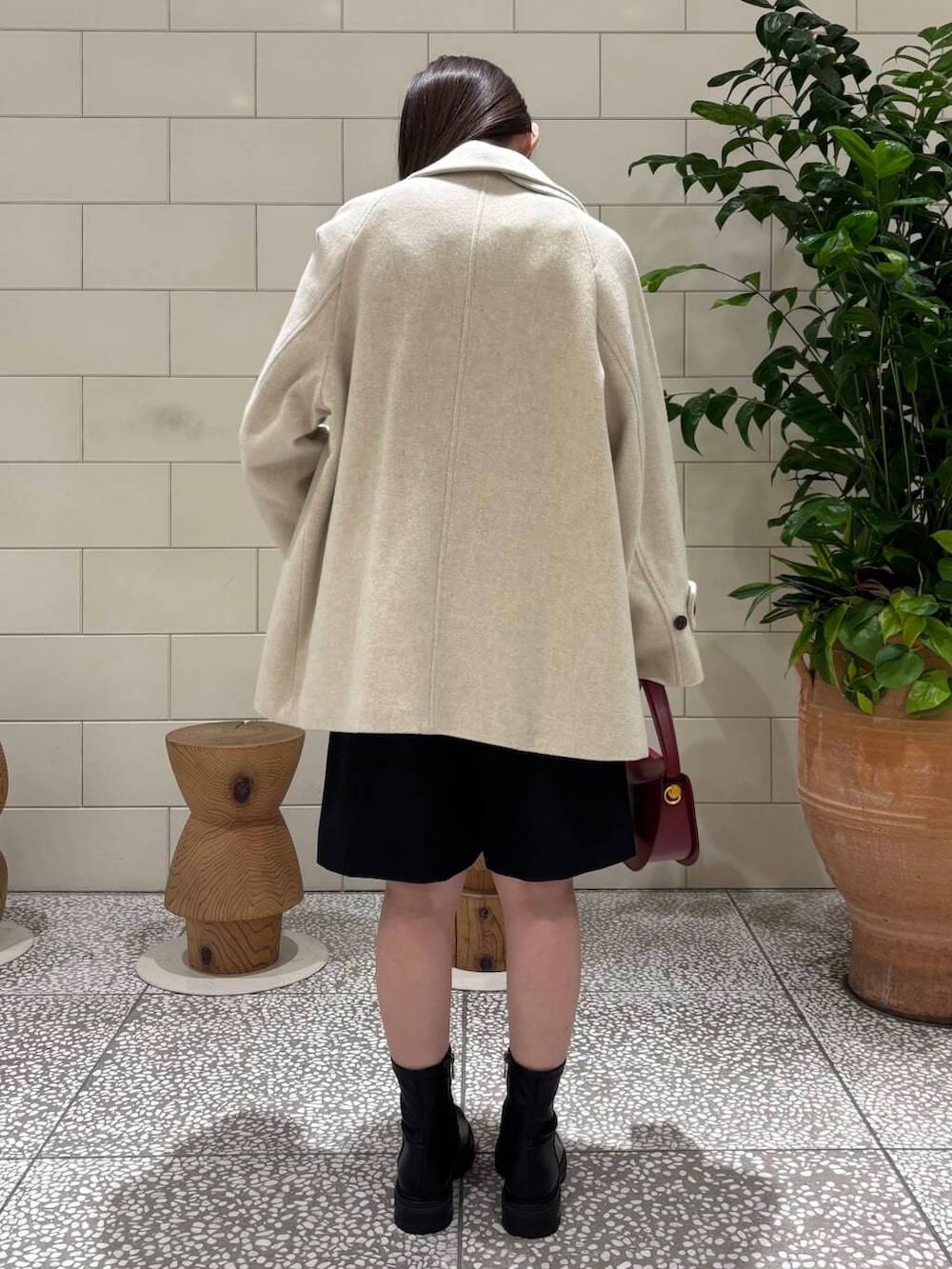 ベージュ系のピーコート、ブラック系のブーツ、ブラック系のその他パンツを着用したレディースの秋コーディネートの3枚目の写真