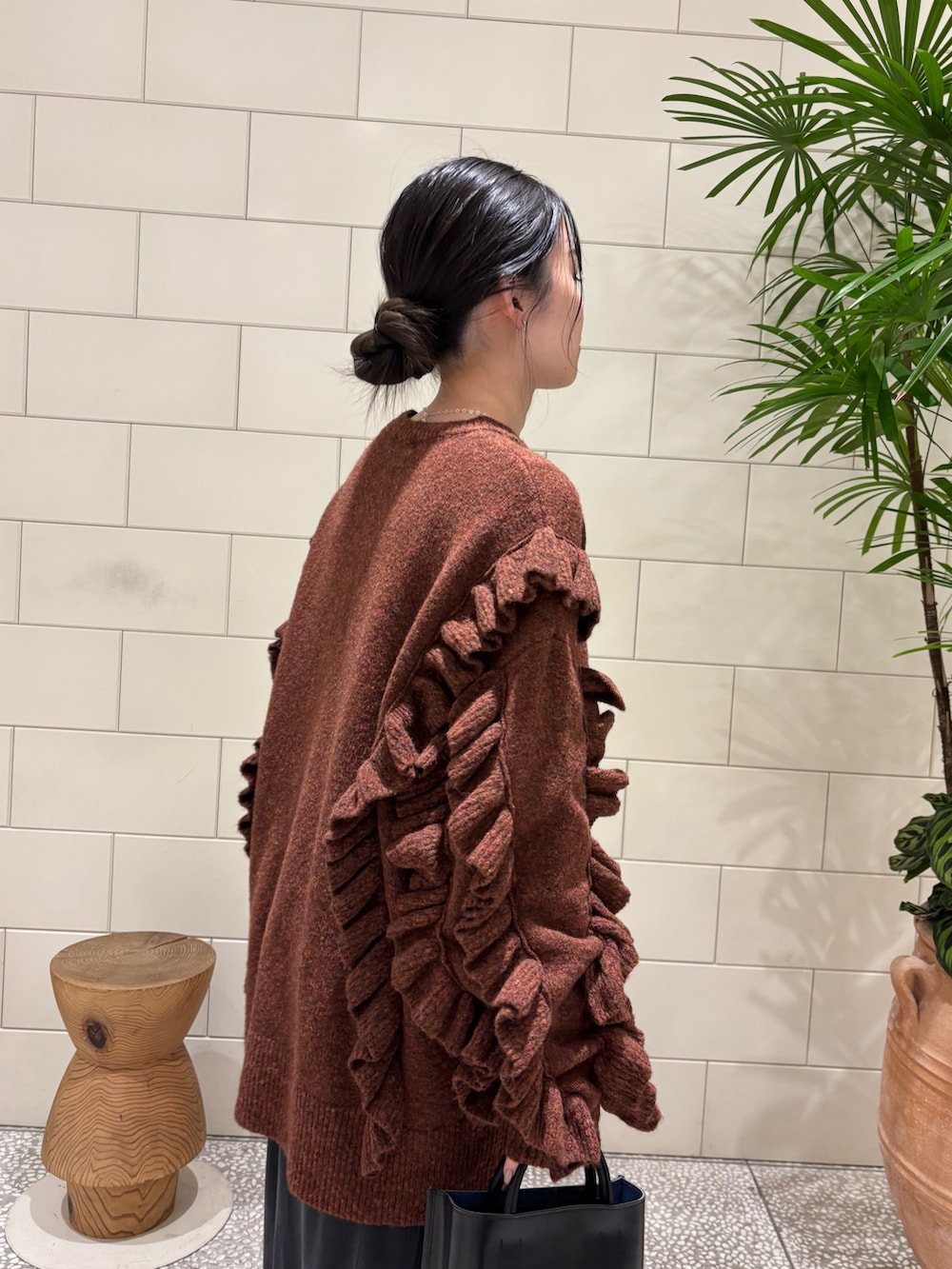 ブラウン系のニット/セーター、ホワイト系のダウンジャケット/コート、ブラック系のトートバッグを着用したレディースの冬コーディネートの2枚目の写真