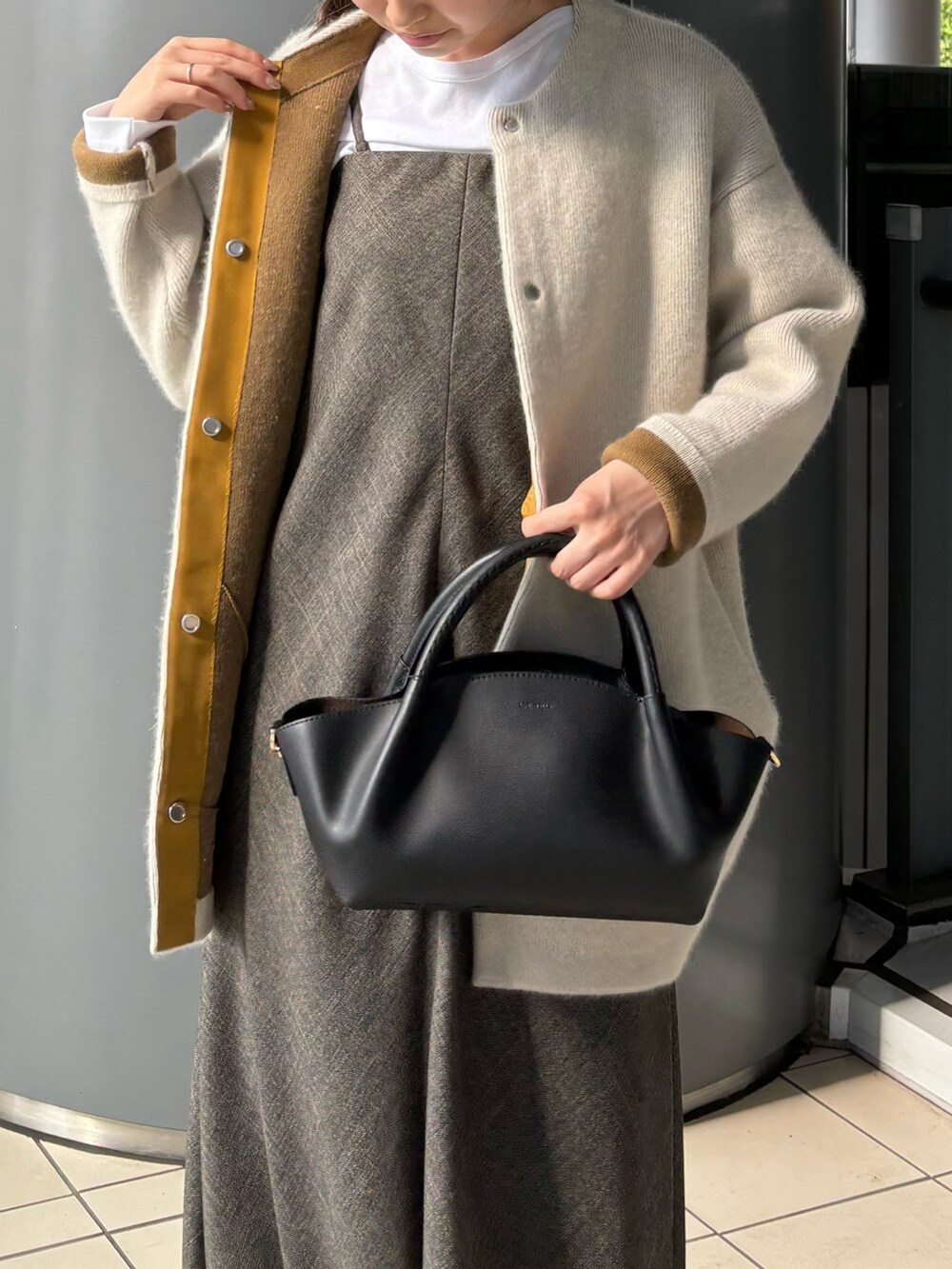 ブラウン系のワンピース、ブラック系のショルダーバッグ、ホワイト系のTシャツ/カットソーを着用したレディースの秋コーディネートの6枚目の写真