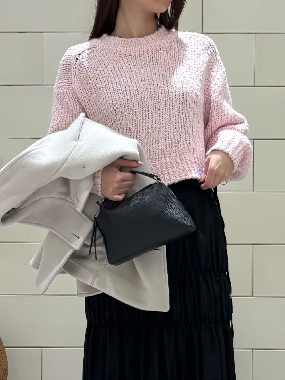 ピンク系のニット/セーター、ブラック系のスカート、ホワイト系のその他アウターを着用したレディースの冬コーディネートの3枚目の写真