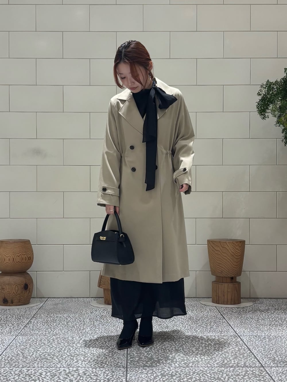 ブラック系のワンピース、ベージュ系のトレンチコート、ブラック系のパンプスを着用したレディースの冬コーディネートの2枚目の写真