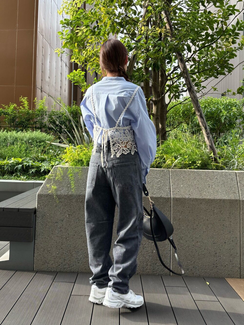 グレー系のデニムパンツ、ホワイト系のスニーカー、ブラック系のハンドバッグを着用したレディースの秋コーディネートの3枚目の写真