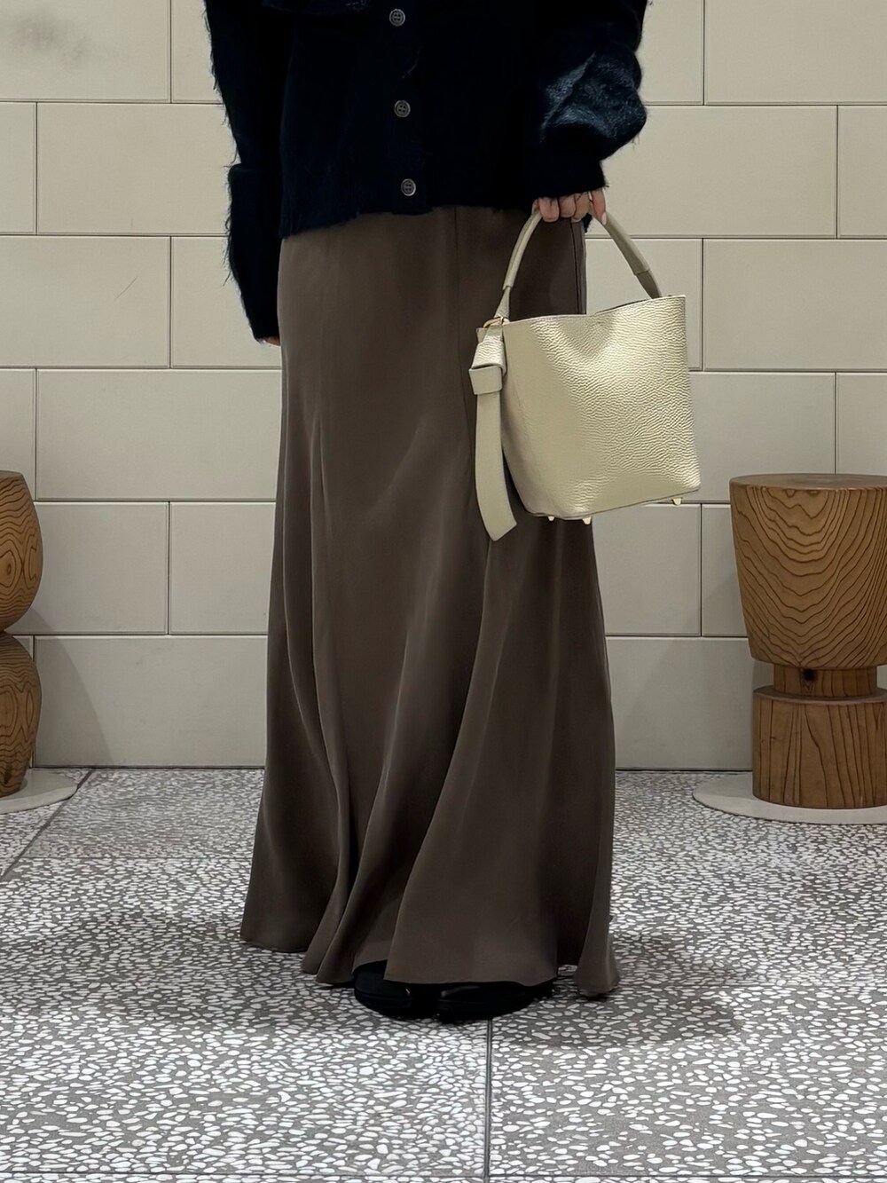 ブラウン系のスカート、ブラック系のブーツ、グリーン系のニット/セーターを着用したレディースの秋コーディネートの4枚目の写真