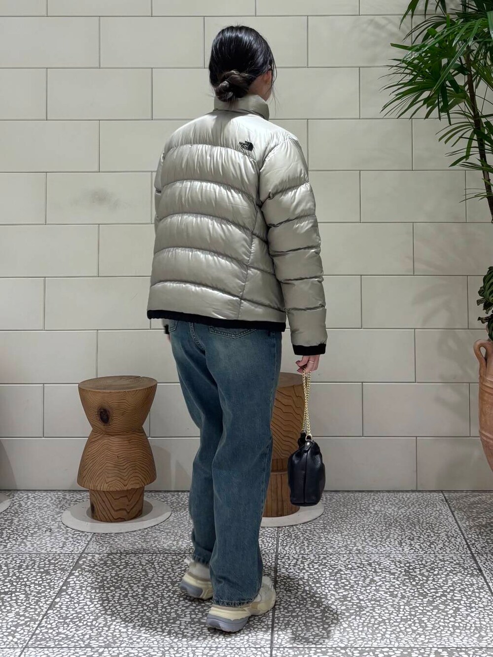 ホワイト系のスニーカー、グレー系のダウンジャケット/コート、ブルー系のデニムパンツを着用したレディースの冬コーディネートの4枚目の写真