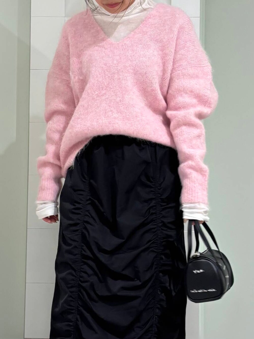 ホワイト系のTシャツ/カットソー、ブラック系のボストンバッグ、ブラック系のスカートを着用したレディースの冬コーディネートの4枚目の写真