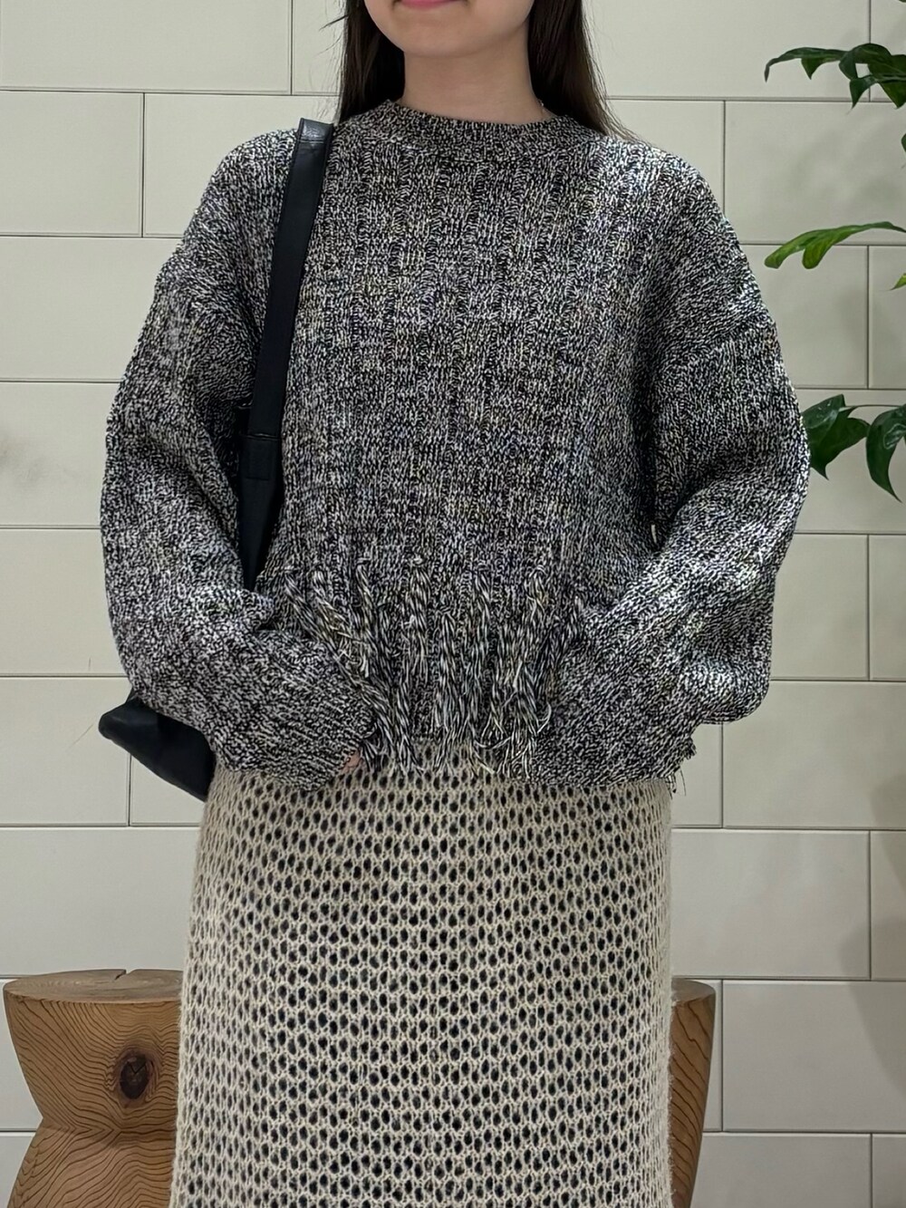 ブラック系のニット/セーター、ブルー系のデニムパンツ、ブラック系のブーツを着用したレディースの秋コーディネートの5枚目の写真