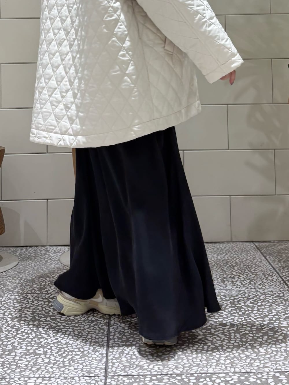 ブラウン系のニット/セーター、ホワイト系のダウンジャケット/コート、ブラック系のトートバッグを着用したレディースの冬コーディネートの3枚目の写真