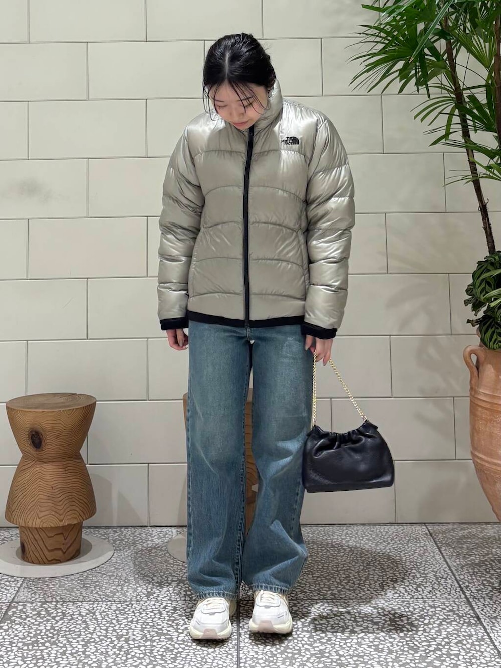 ホワイト系のスニーカー、グレー系のダウンジャケット/コート、ブルー系のデニムパンツを着用したレディースの冬コーディネートの2枚目の写真