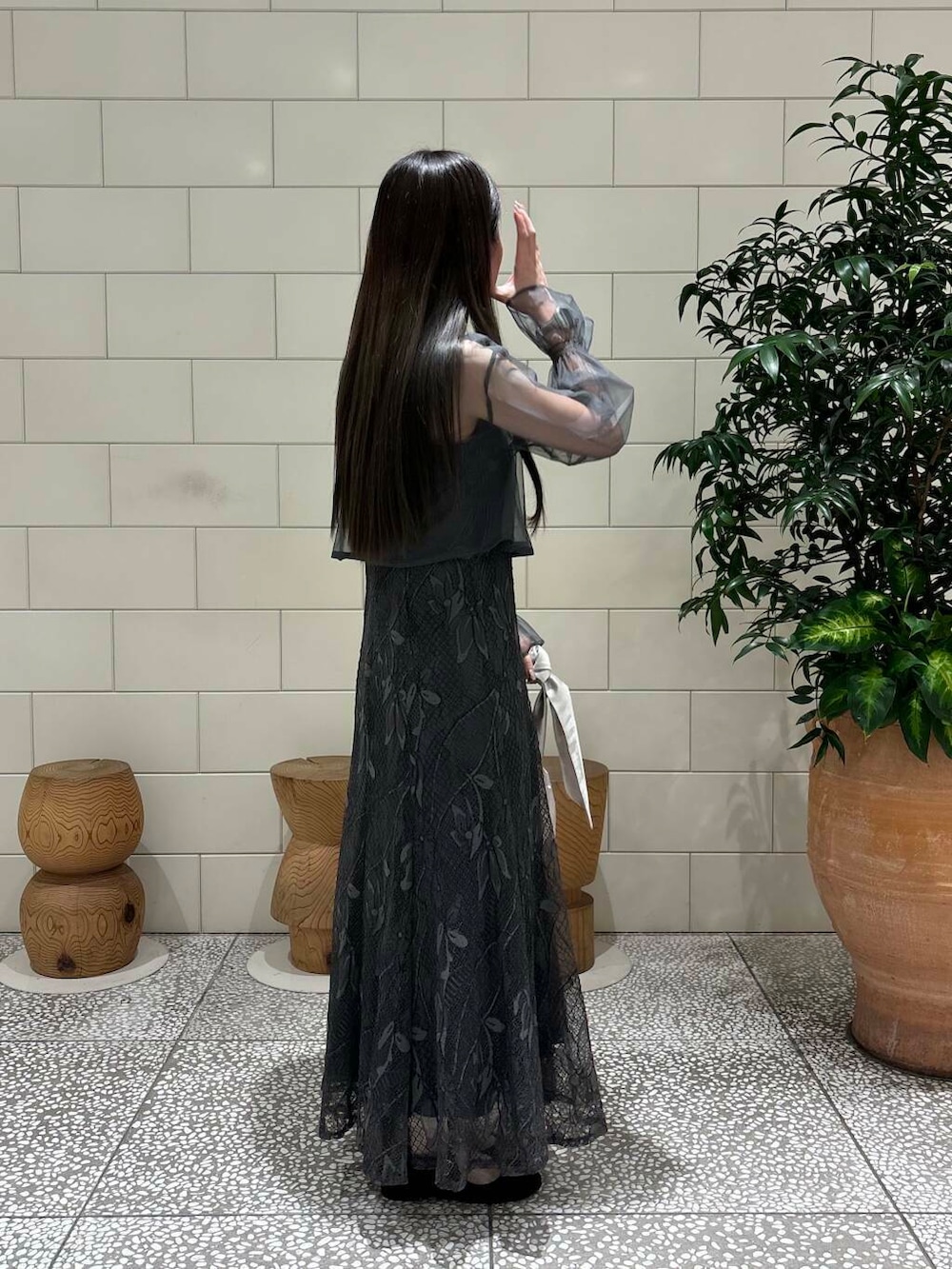 グレー系のワンピース、ベージュ系のハンドバッグ、ブラック系のパンプスを着用したレディースの秋コーディネートの2枚目の写真