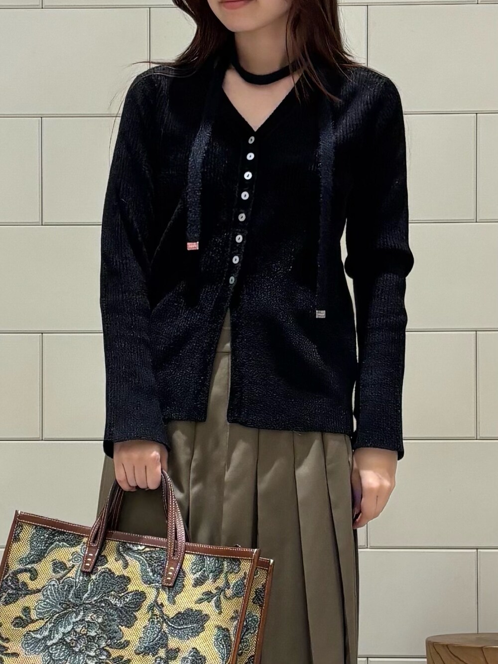 ブラック系のカーディガン/ボレロ、グリーン系のスカート、ブラウン系のハンドバッグを着用したレディースの秋コーディネートの4枚目の写真