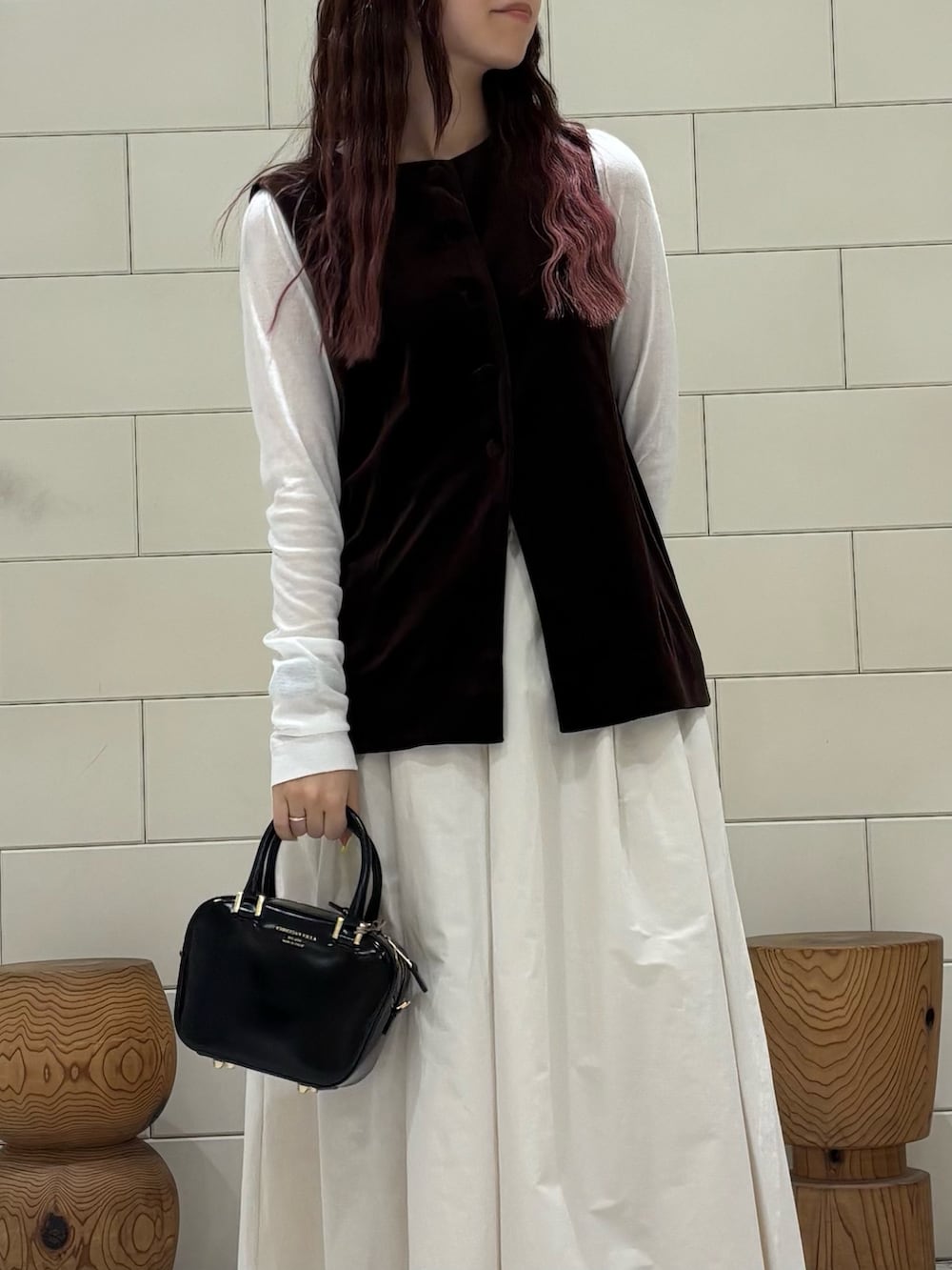 ホワイト系のTシャツ/カットソー、ブラウン系のベスト、ホワイト系のスカートを着用したレディースの秋コーディネートの3枚目の写真