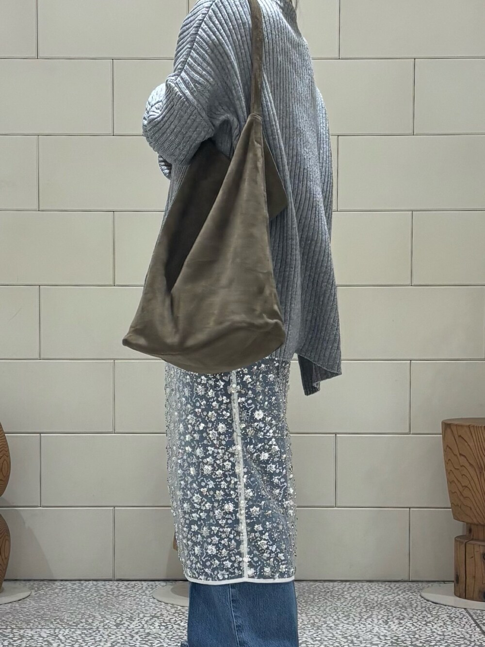 グレー系のニット/セーター、ホワイト系のスカート、ブルー系のデニムパンツを着用したレディースの冬コーディネートの5枚目の写真