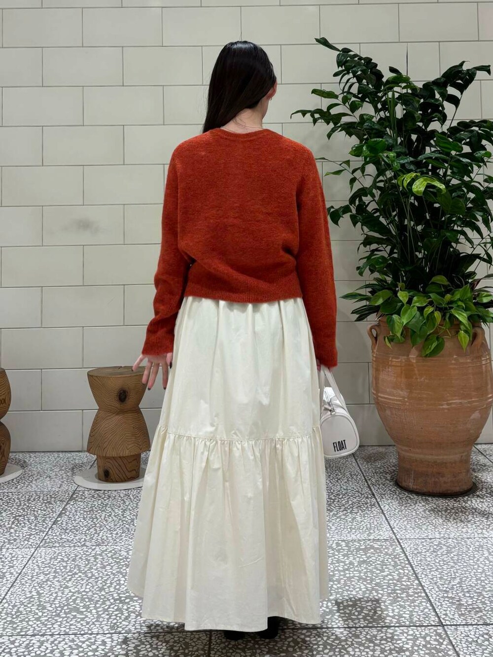 ホワイト系のスカート、ホワイト系のボストンバッグ、ブラック系のブーツを着用したレディースの秋コーディネートの4枚目の写真