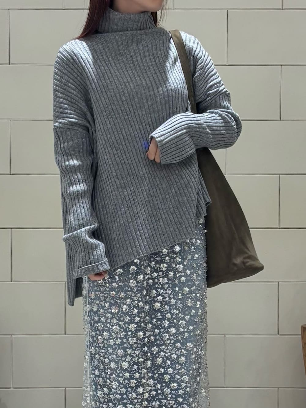 グレー系のニット/セーター、ホワイト系のスカート、ブルー系のデニムパンツを着用したレディースの冬コーディネートの3枚目の写真