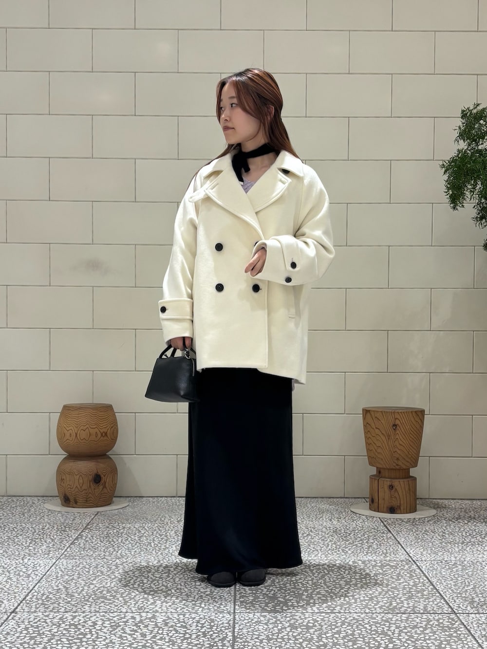 パープル系のニット/セーター、ホワイト系のピーコート、ブラック系のスカートを着用したレディースの冬コーディネートの2枚目の写真