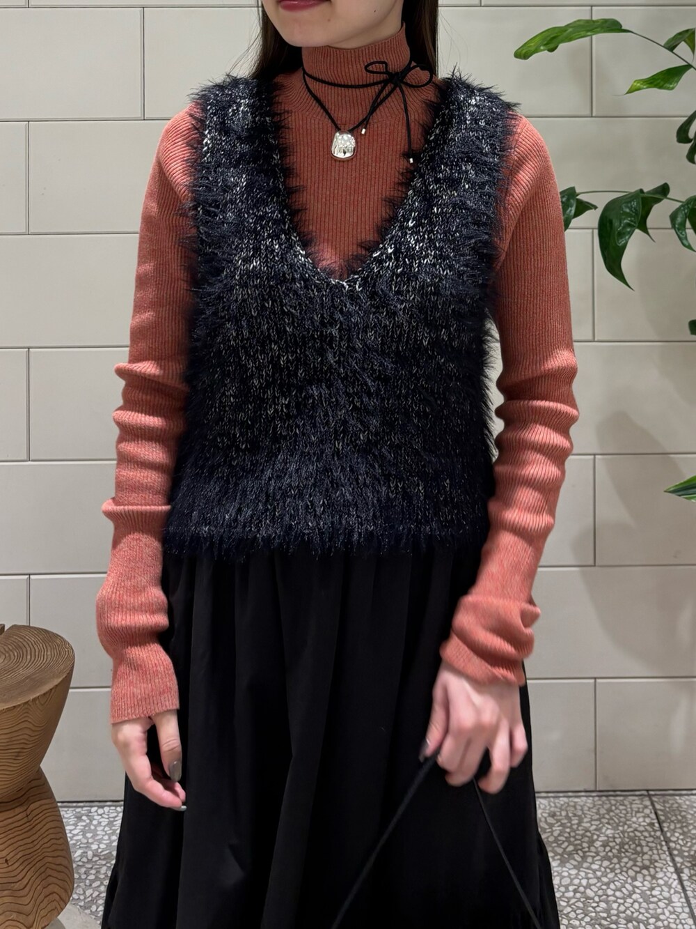 オレンジ系のニット/セーター、ブラック系のベスト、ブラック系のハンドバッグを着用したレディースの秋コーディネートの5枚目の写真