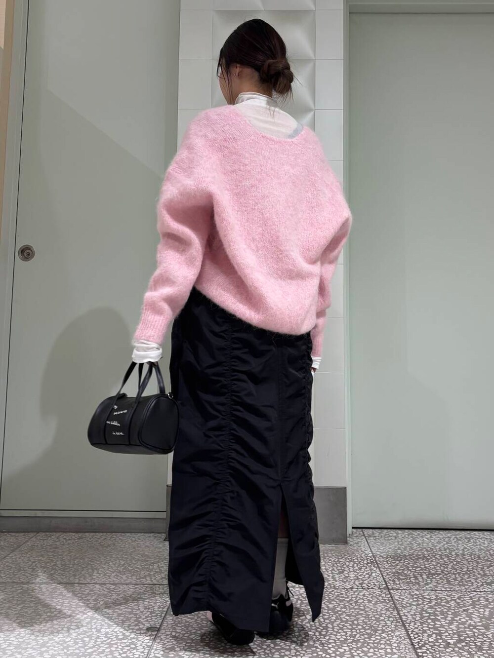 ホワイト系のTシャツ/カットソー、ブラック系のボストンバッグ、ブラック系のスカートを着用したレディースの冬コーディネートの3枚目の写真