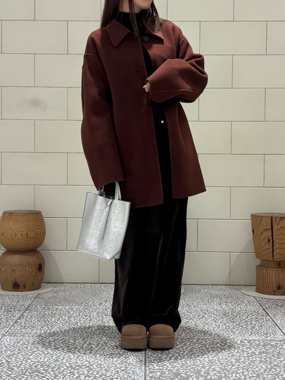 ブラック系のTシャツ/カットソー、ブラウン系のステンカラーコート、シルバー系のトートバッグを着用したレディースの冬コーディネートの4枚目の写真