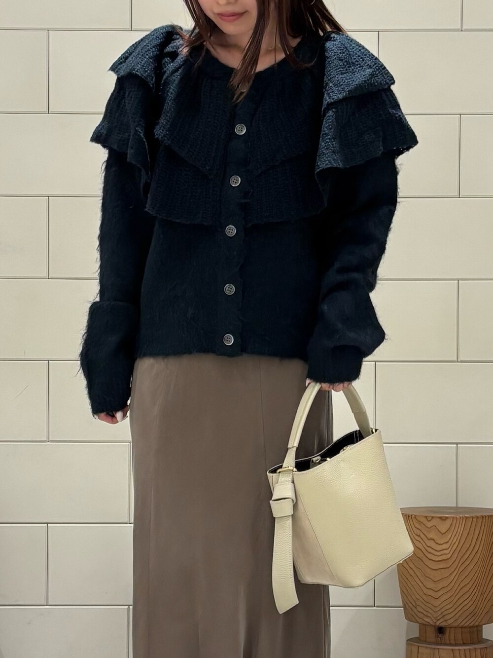 ブラウン系のスカート、ブラック系のブーツ、グリーン系のニット/セーターを着用したレディースの秋コーディネートの2枚目の写真