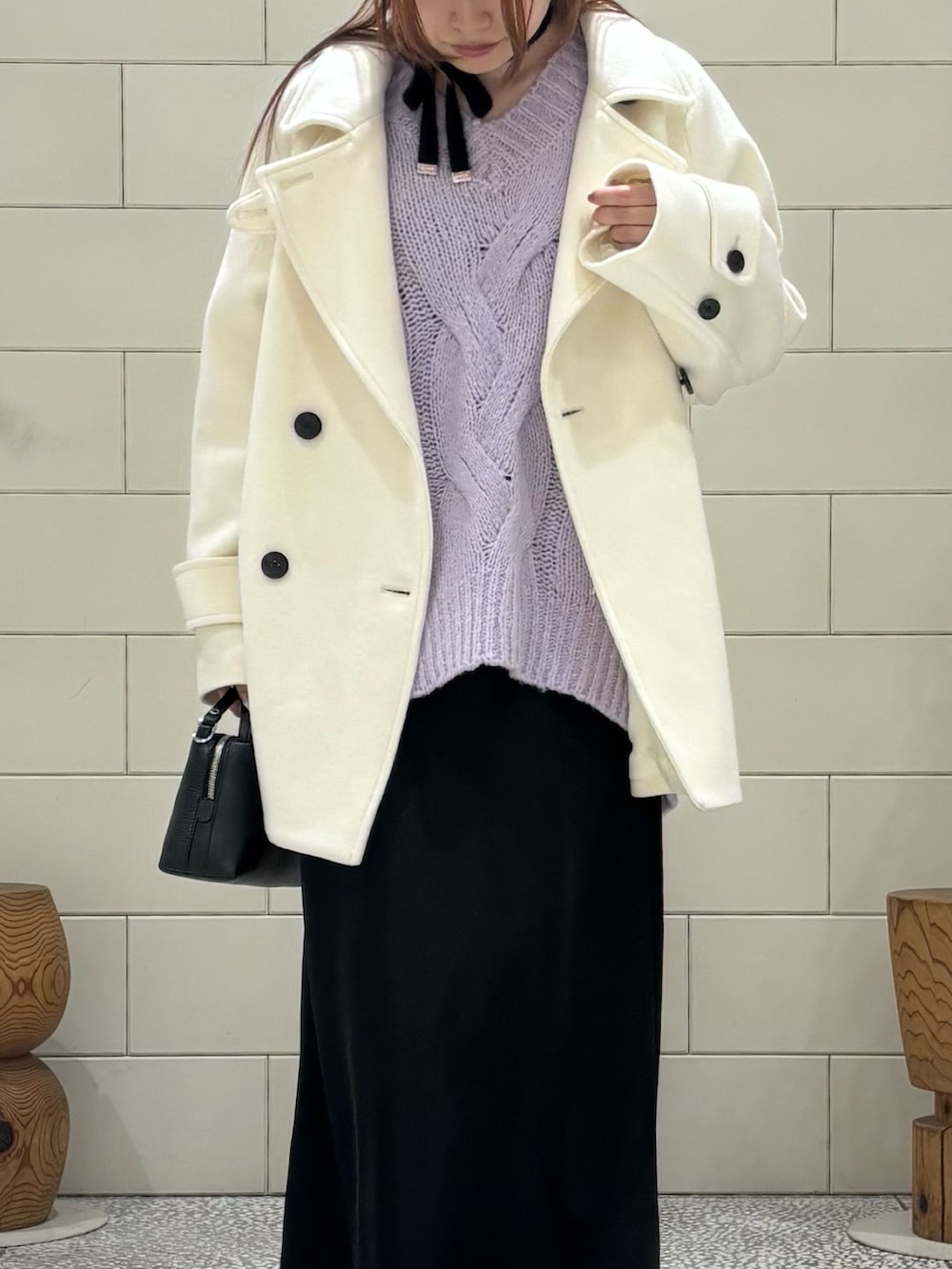 パープル系のニット/セーター、ホワイト系のピーコート、ブラック系のスカートを着用したレディースの冬コーディネートの4枚目の写真