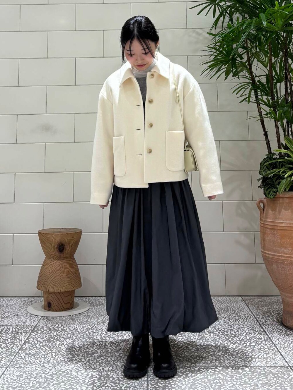 ブラック系のブーツ、ホワイト系のその他アウター、グレー系のカーディガン/ボレロを着用したレディースの冬コーディネートの2枚目の写真