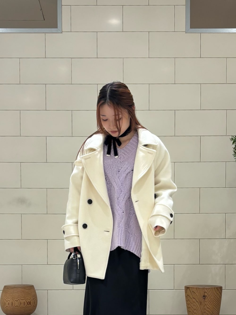 パープル系のニット/セーター、ホワイト系のピーコート、ブラック系のスカートを着用したレディースの冬コーディネートの3枚目の写真