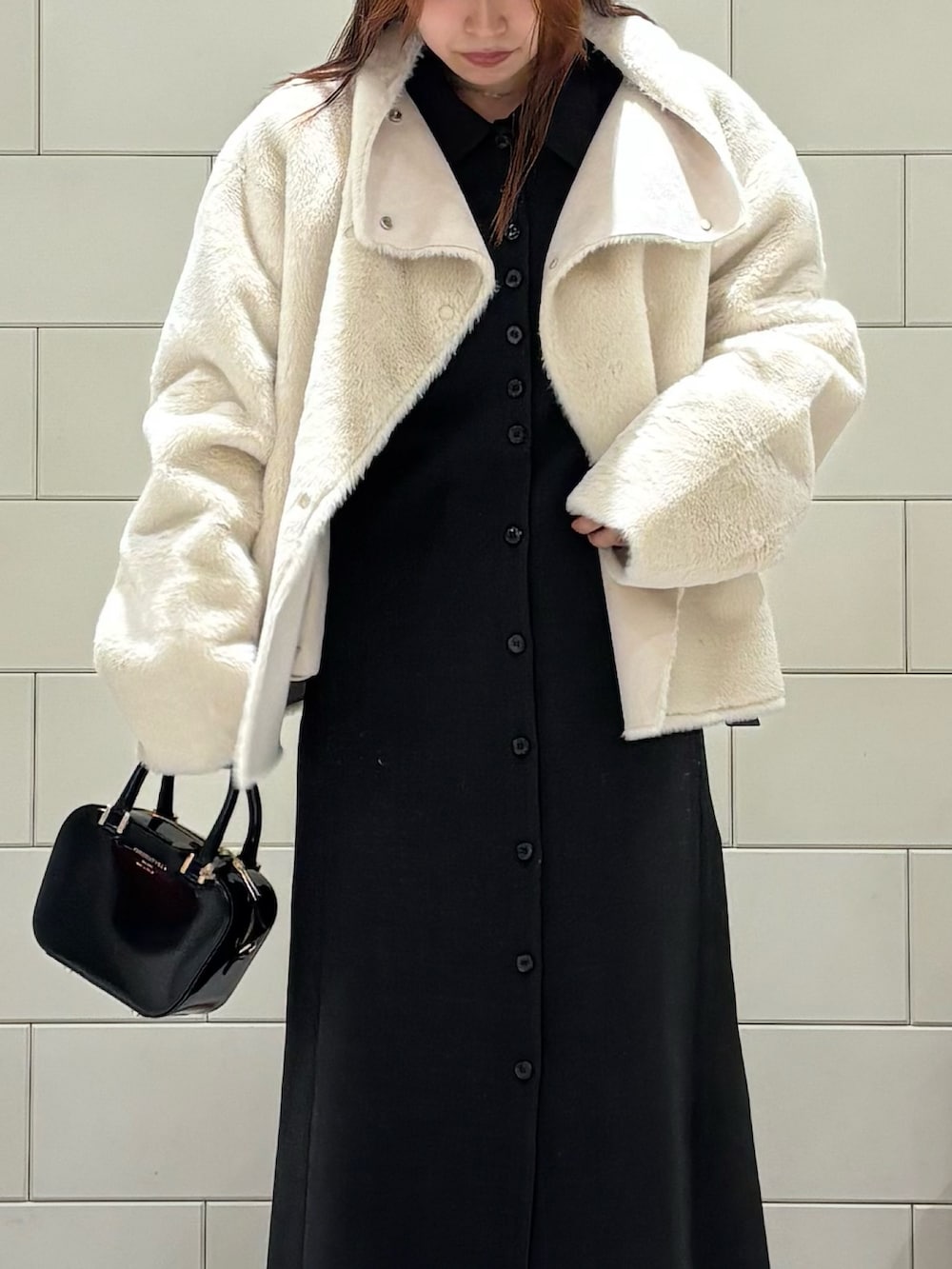 グレー系のワンピース、ホワイト系のブルゾン、ブラック系のショルダーバッグを着用したレディースの冬コーディネートの4枚目の写真