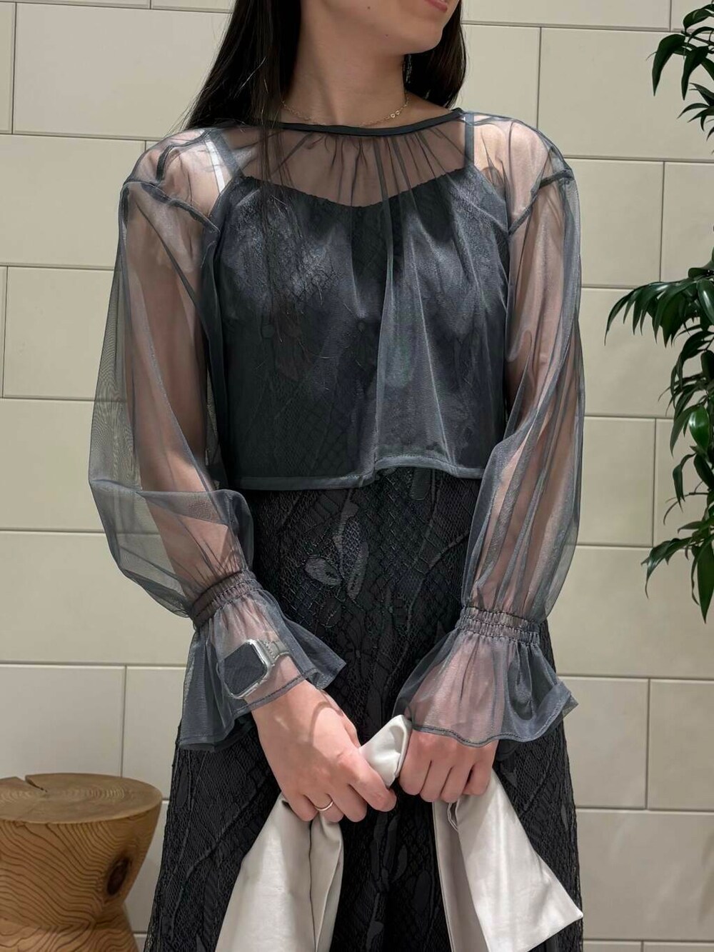 グレー系のワンピース、ベージュ系のハンドバッグ、ブラック系のパンプスを着用したレディースの秋コーディネートの4枚目の写真