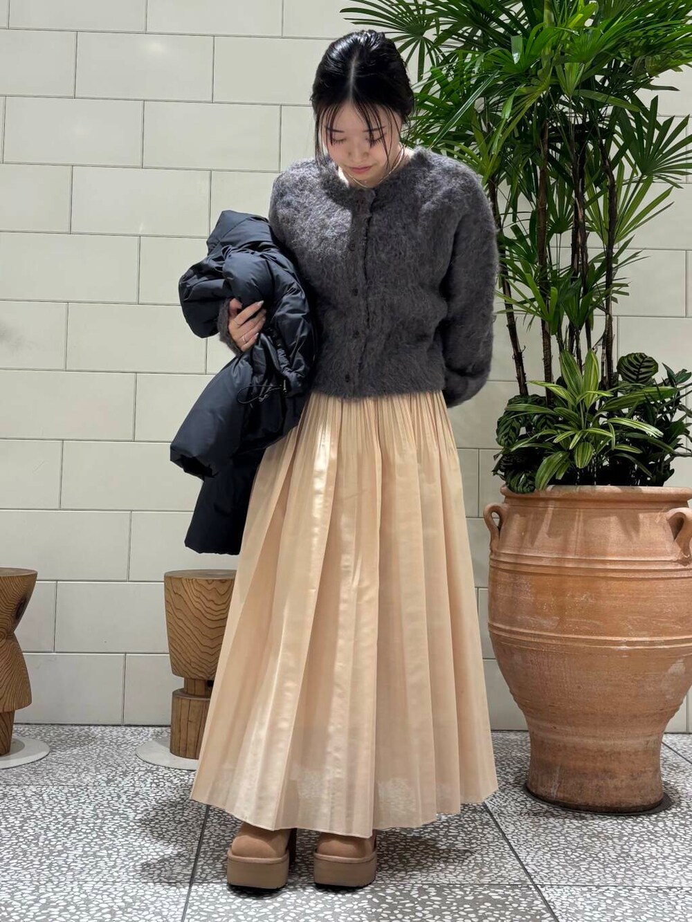 イエロー系のスカート、ブラウン系のカーディガン/ボレロ、ブラウン系のブーツを着用したレディースの冬コーディネートの4枚目の写真