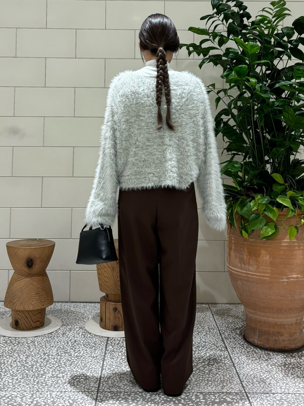 グレー系のニット/セーター、ブラック系のショルダーバッグ、ブラック系のブーツを着用したレディースの秋コーディネートの4枚目の写真