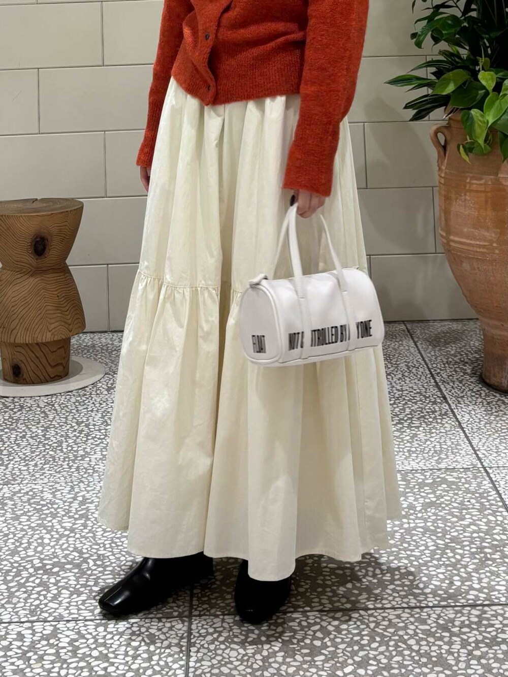 ホワイト系のスカート、ホワイト系のボストンバッグ、ブラック系のブーツを着用したレディースの秋コーディネートの6枚目の写真