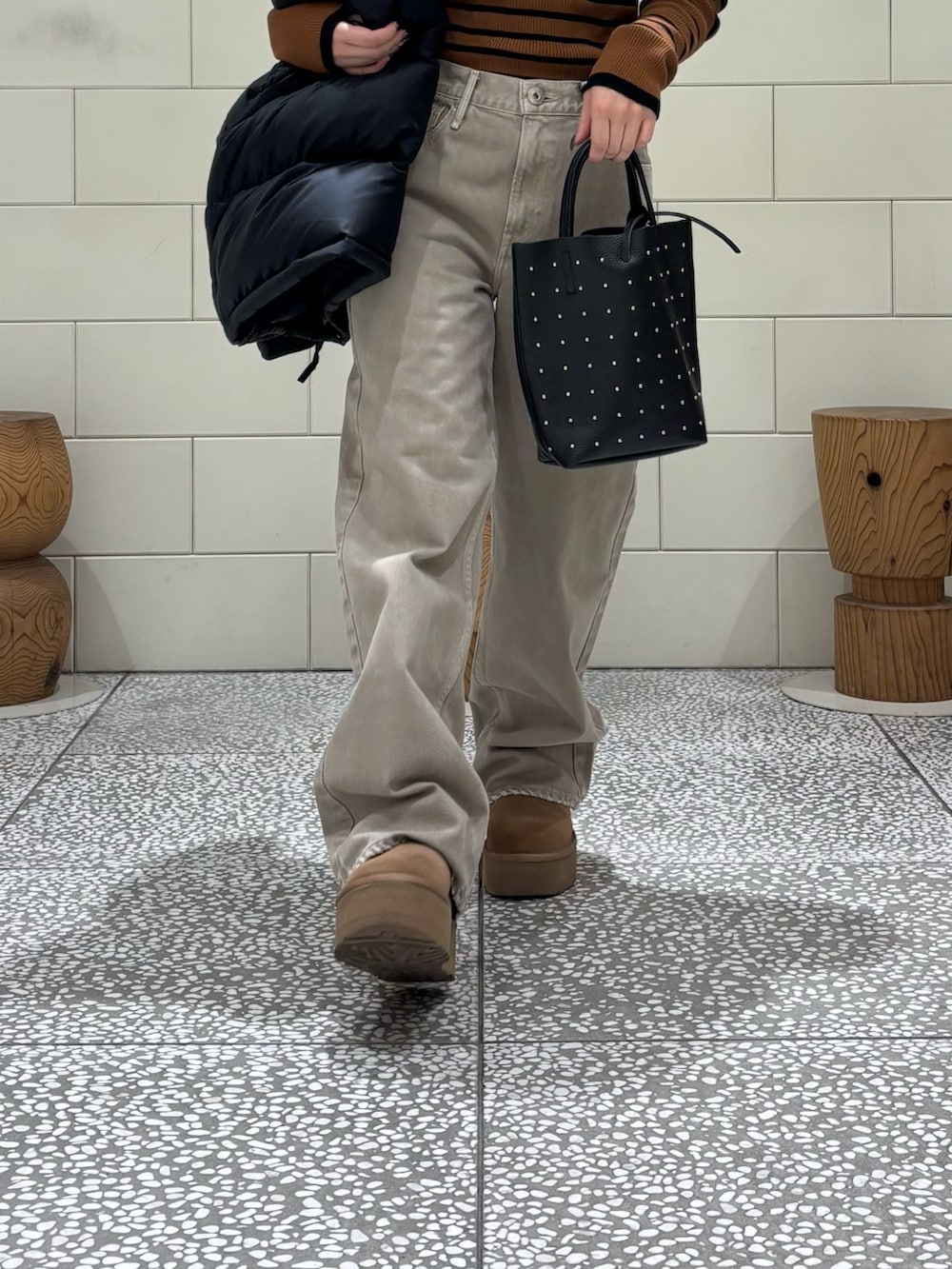 ブラウン系のニット/セーター、ブラック系のダウンジャケット/コート、ベージュ系のデニムパンツを着用したレディースの秋コーディネートの7枚目の写真