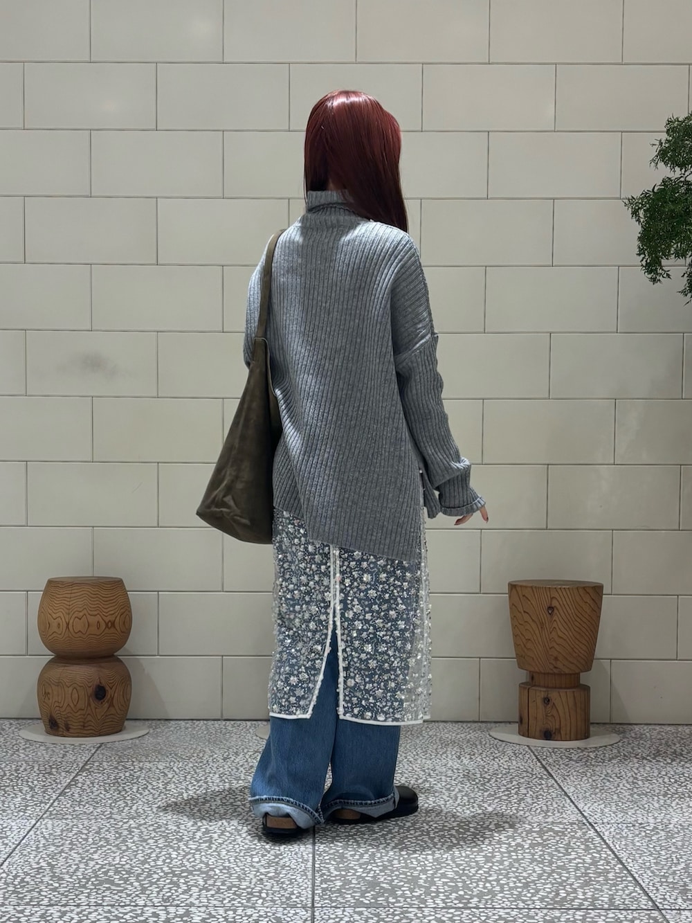 グレー系のニット/セーター、ホワイト系のスカート、ブルー系のデニムパンツを着用したレディースの冬コーディネートの2枚目の写真