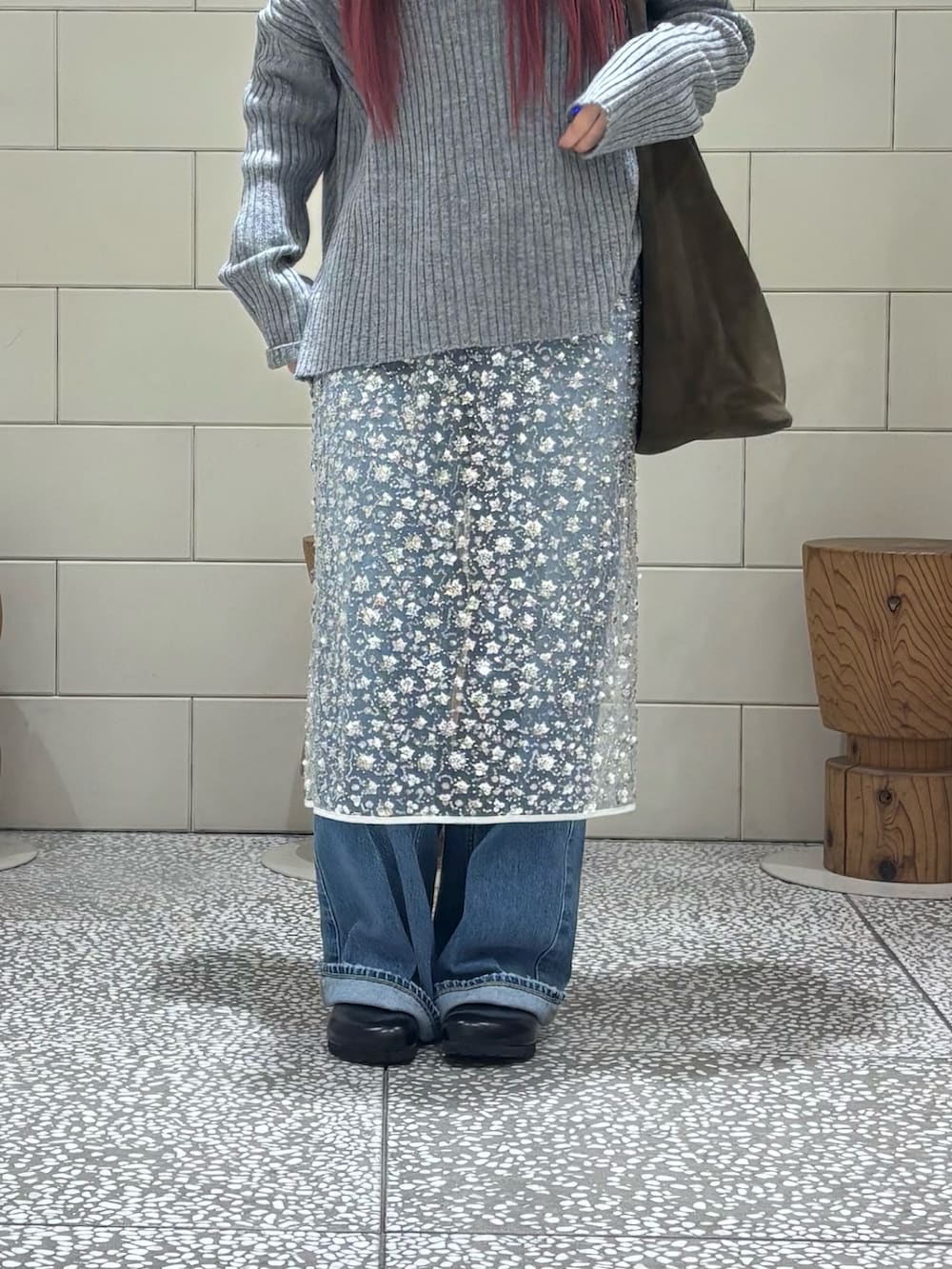 グレー系のニット/セーター、ホワイト系のスカート、ブルー系のデニムパンツを着用したレディースの冬コーディネートの6枚目の写真