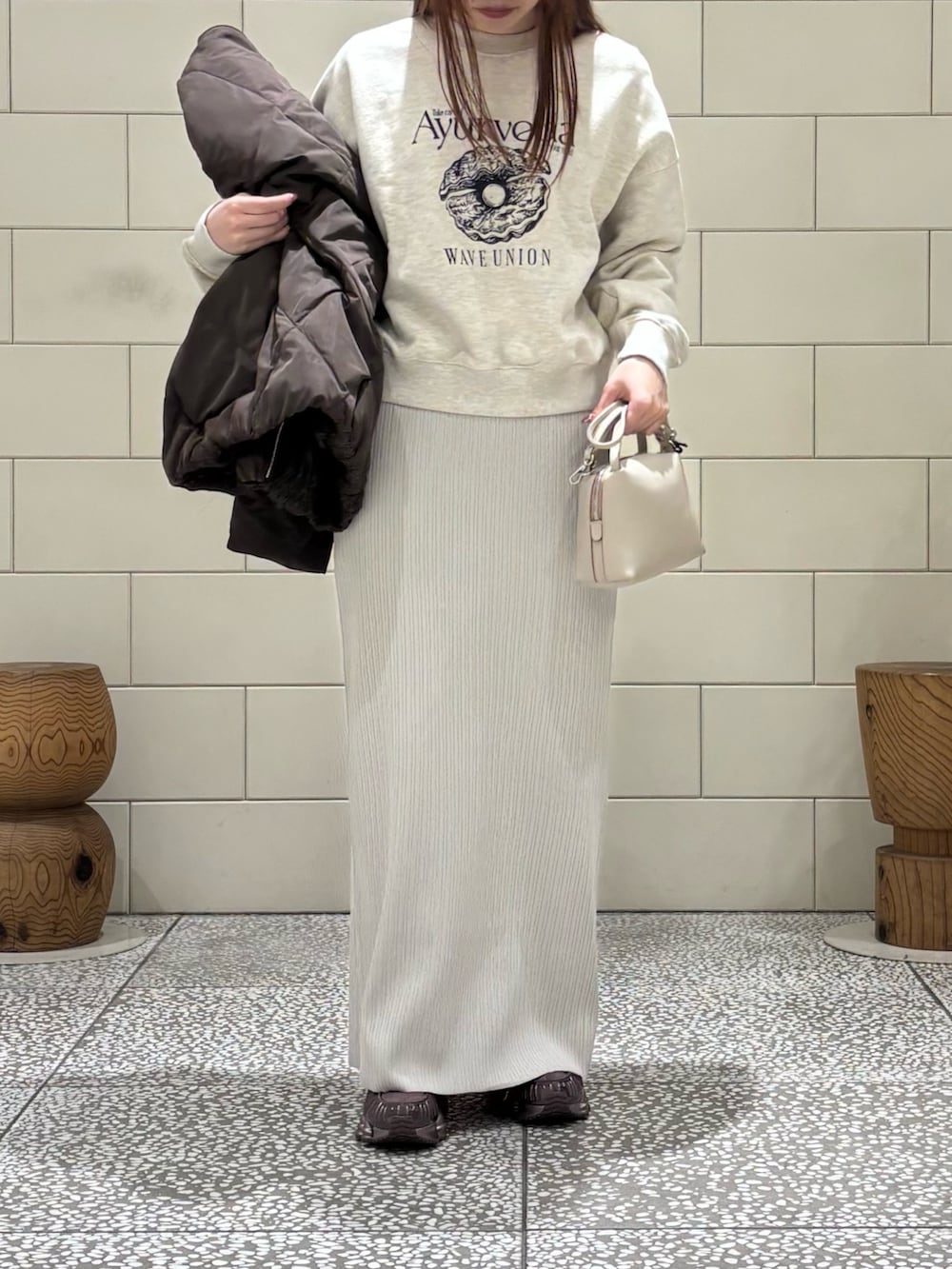 ベージュ系のスウェット、ブラウン系のダウンジャケット/コート、ベージュ系のスカートを着用したレディースの冬コーディネートの4枚目の写真