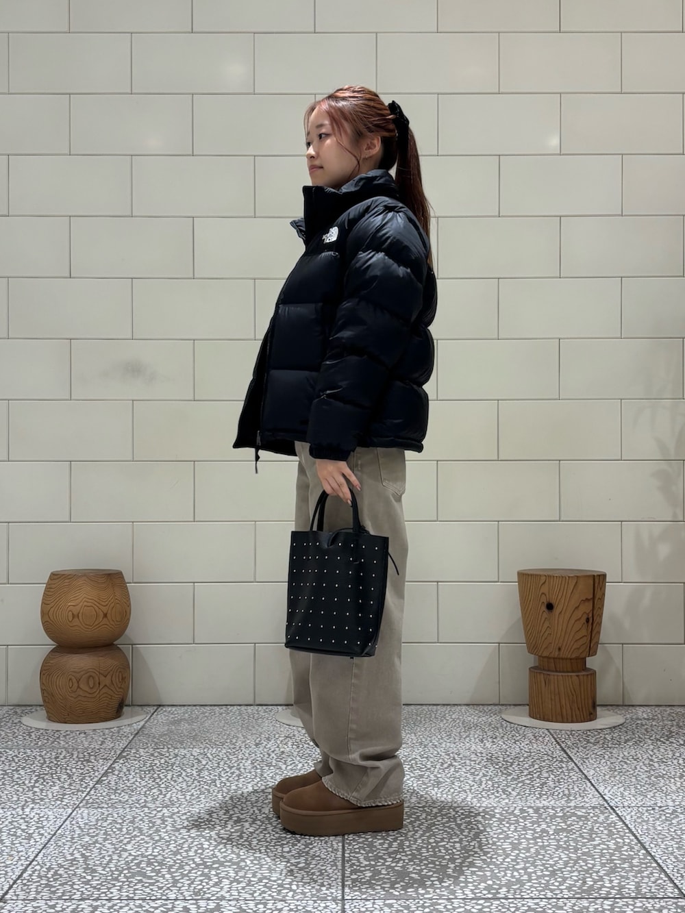 ブラウン系のニット/セーター、ブラック系のダウンジャケット/コート、ベージュ系のデニムパンツを着用したレディースの秋コーディネートの3枚目の写真