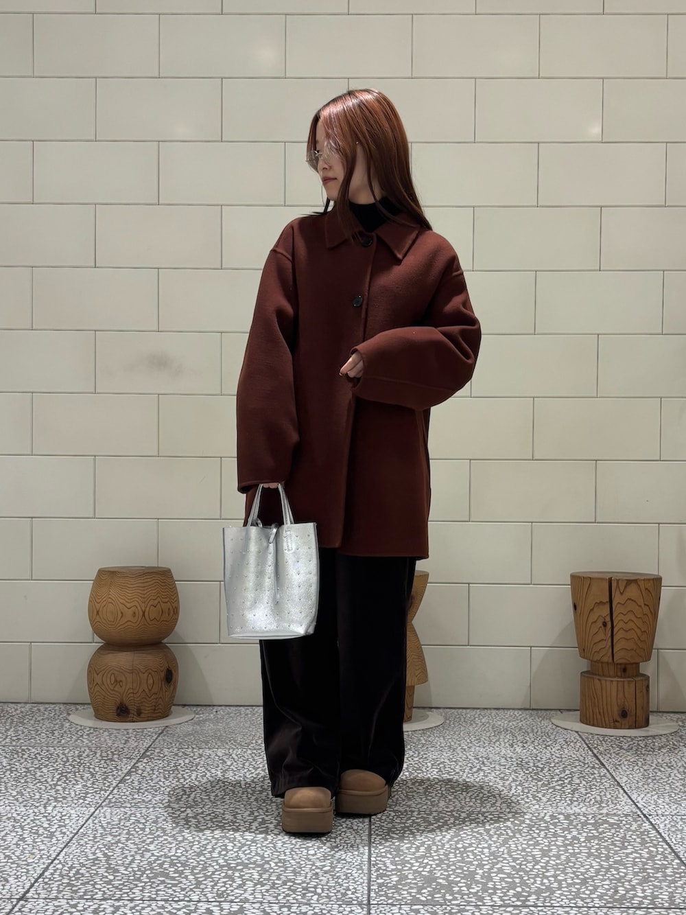 ブラック系のTシャツ/カットソー、ブラウン系のステンカラーコート、シルバー系のトートバッグを着用したレディースの冬コーディネートの2枚目の写真