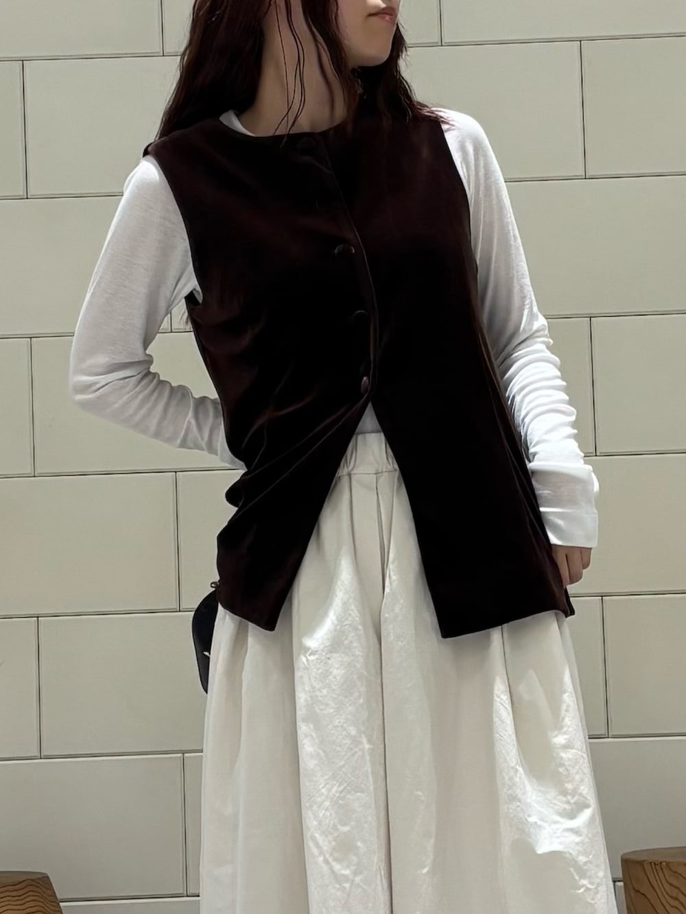 ホワイト系のTシャツ/カットソー、ブラウン系のベスト、ホワイト系のスカートを着用したレディースの秋コーディネートの4枚目の写真