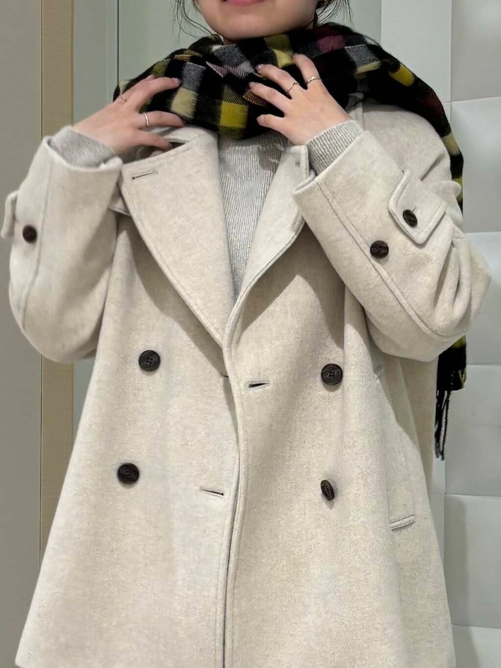 ベージュ系のピーコート、ホワイト系のTシャツ/カットソー、ブラック系のデニムパンツを着用したレディースの冬コーディネートの6枚目の写真