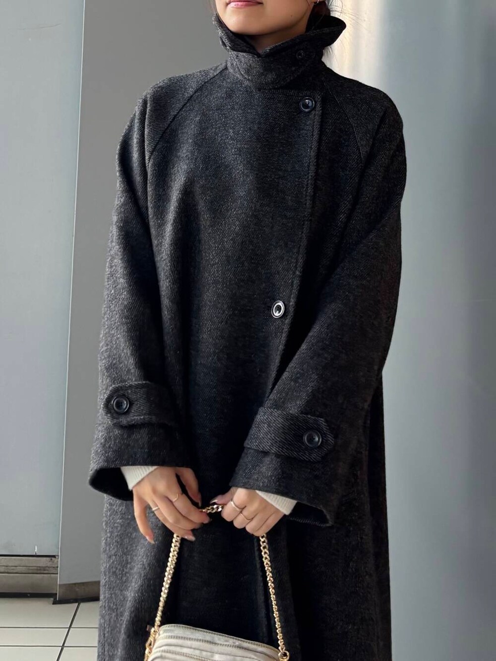 ブラック系のステンカラーコート、ホワイト系のショルダーバッグ、ブラウン系のスカートを着用したレディースの冬コーディネートの6枚目の写真