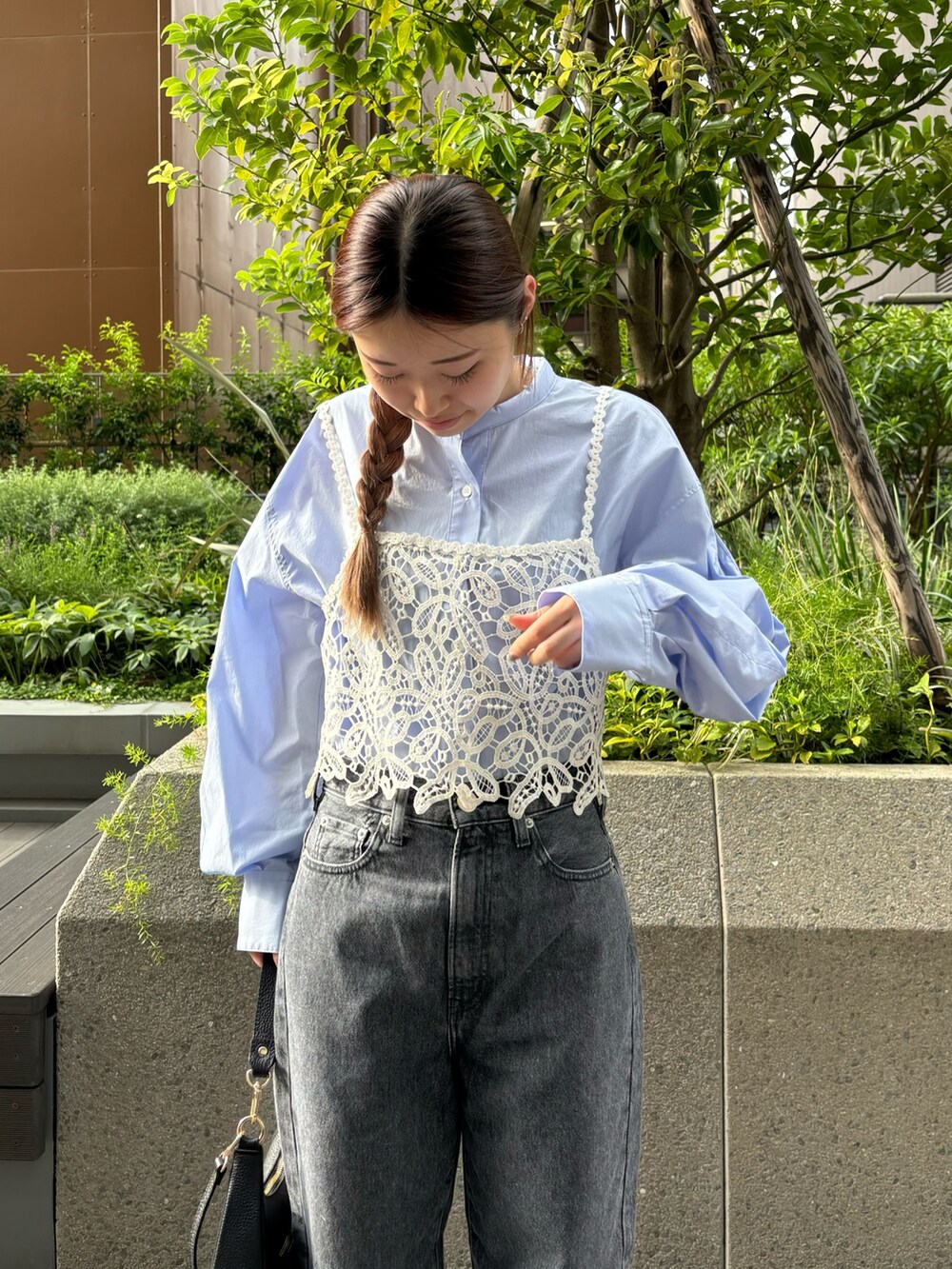 グレー系のデニムパンツ、ホワイト系のスニーカー、ブラック系のハンドバッグを着用したレディースの秋コーディネートの4枚目の写真