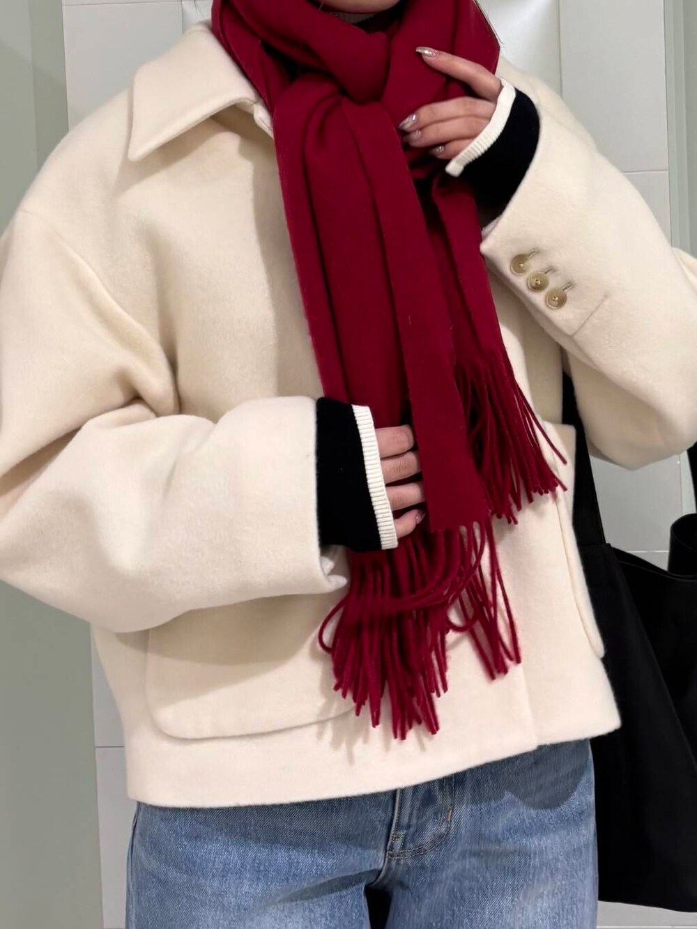 ブラック系のニット/セーター、ブルー系のデニムパンツ、ホワイト系のその他アウターを着用したレディースの秋コーディネートの4枚目の写真