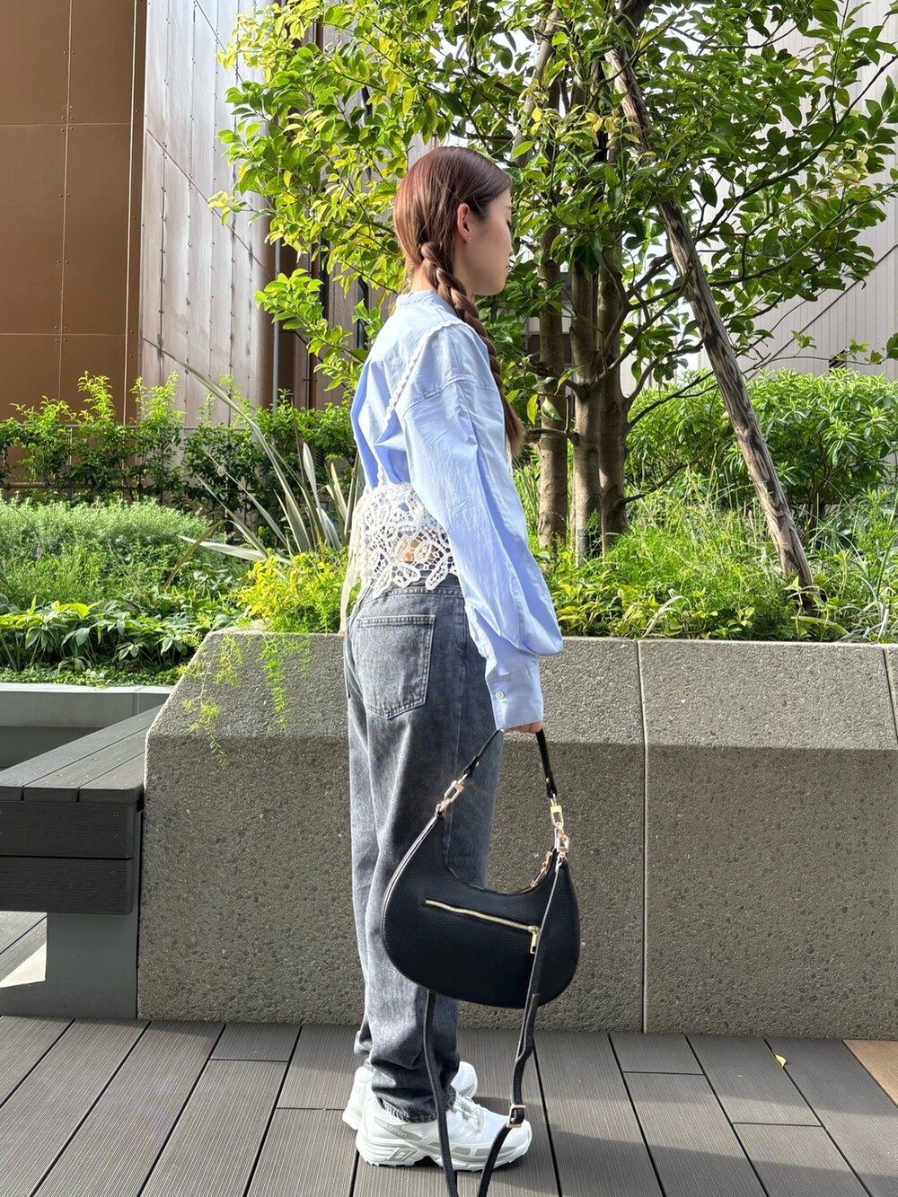 グレー系のデニムパンツ、ホワイト系のスニーカー、ブラック系のハンドバッグを着用したレディースの秋コーディネートの2枚目の写真