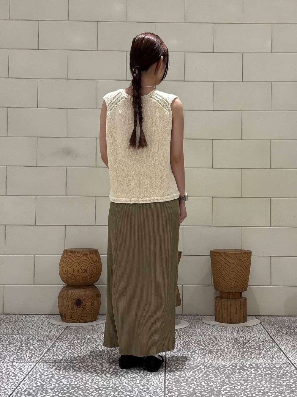 ゴールド系のかごバッグ、ホワイト系のベスト、ベージュ系のスカートを着用したレディースの夏コーディネートの3枚目の写真