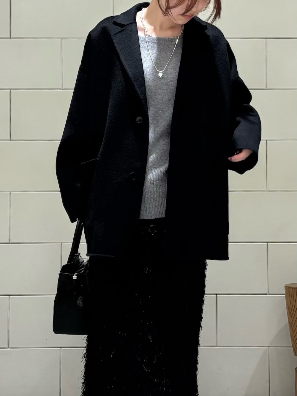 ブラック系のその他アウター、グレー系のニット/セーター、ブラック系のスカートを着用したレディースの秋コーディネートの5枚目の写真