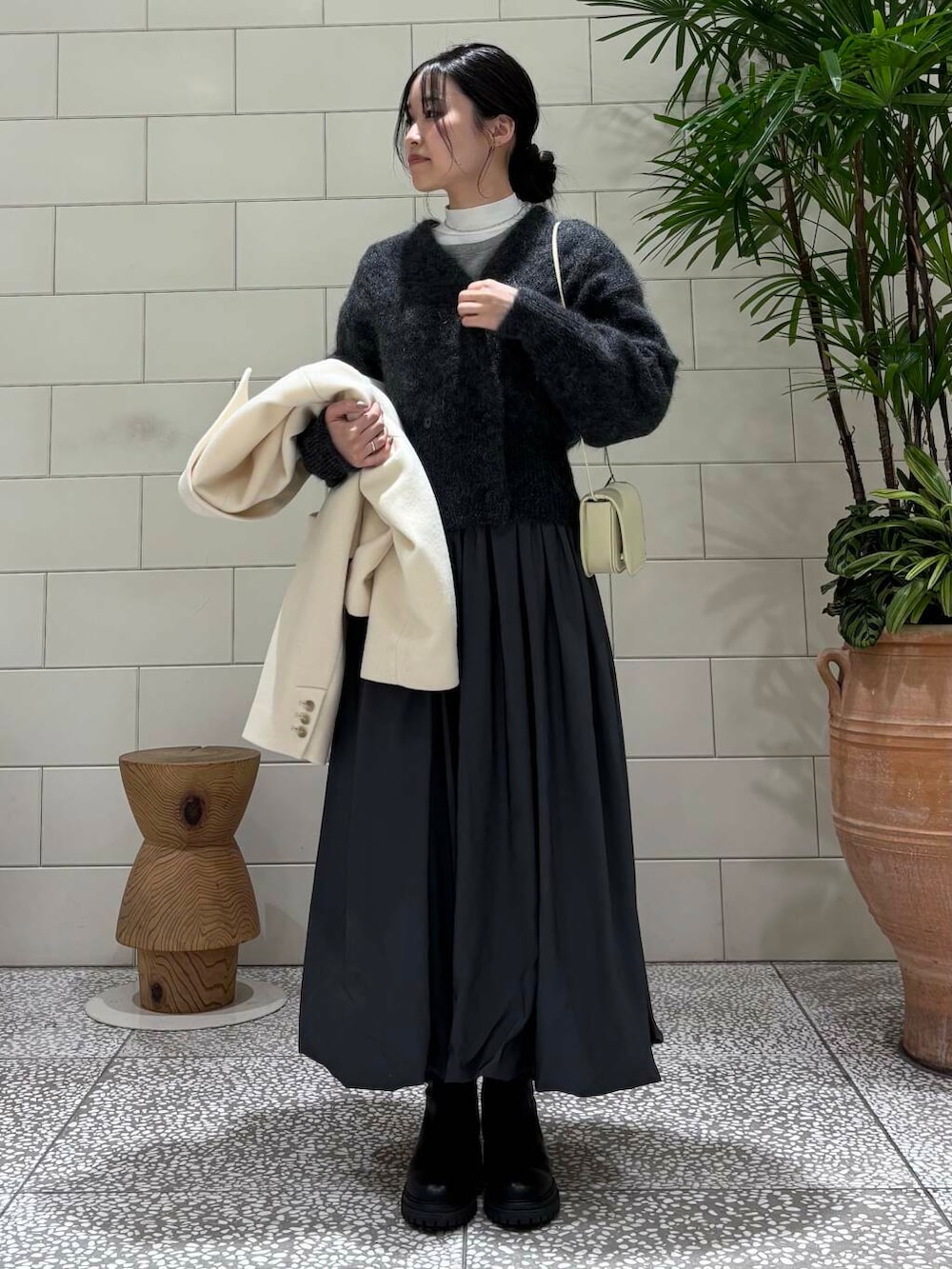 ブラック系のブーツ、ホワイト系のその他アウター、グレー系のカーディガン/ボレロを着用したレディースの冬コーディネートの5枚目の写真