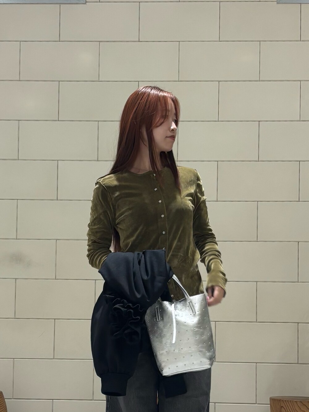 ブラック系のブルゾン、グリーン系のカーディガン/ボレロ、ブラック系のデニムパンツを着用したレディースの冬コーディネートの3枚目の写真