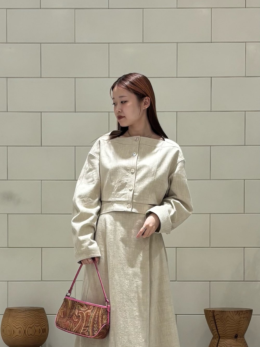 ベージュ系のその他アウター、ベージュ系のスカート、オレンジ系のハンドバッグを着用したレディースの春コーディネートの3枚目の写真