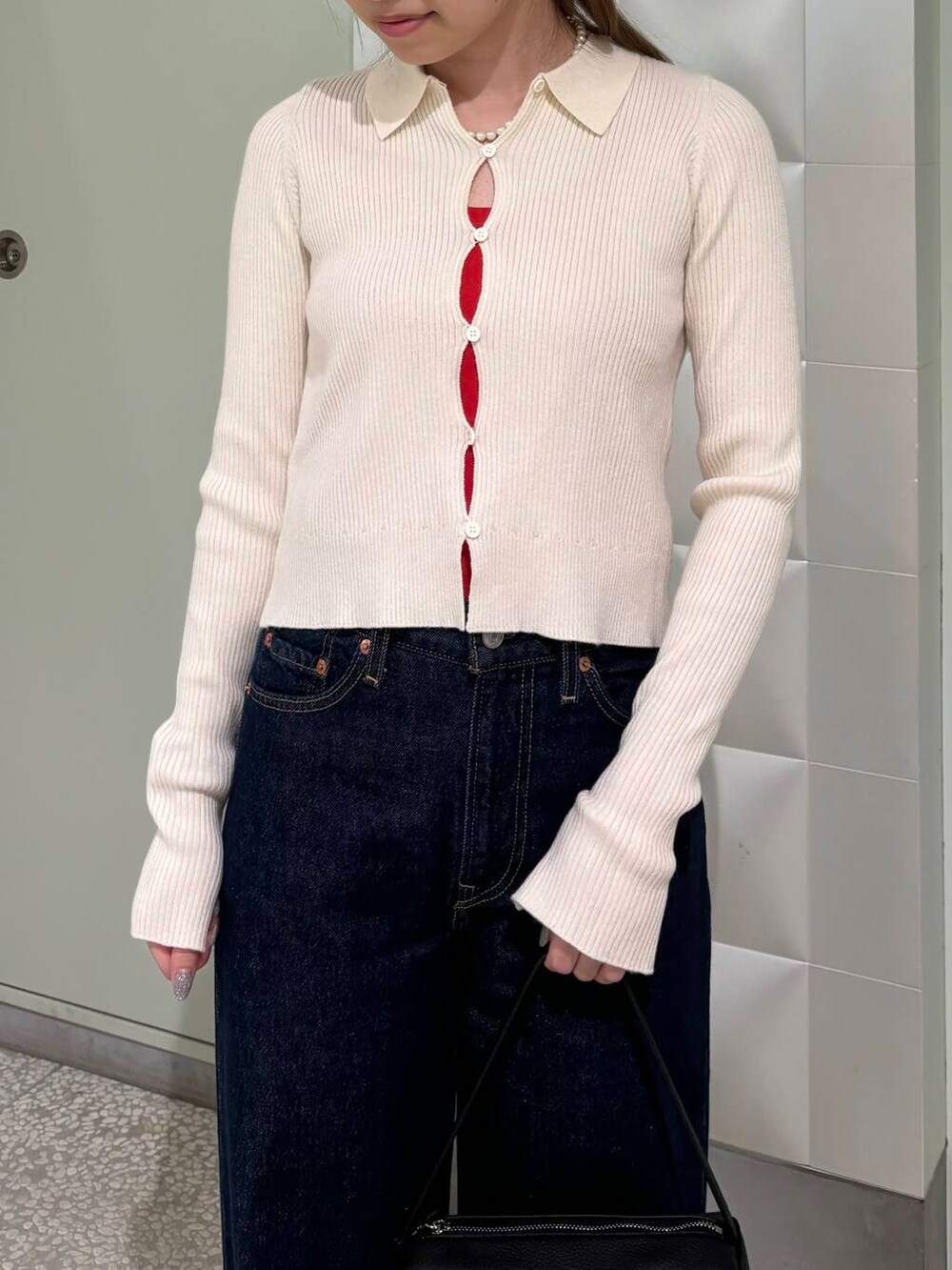 ブルー系のデニムパンツ、オレンジ系のタンクトップ、ブラック系のハンドバッグを着用したレディースの夏コーディネートの5枚目の写真